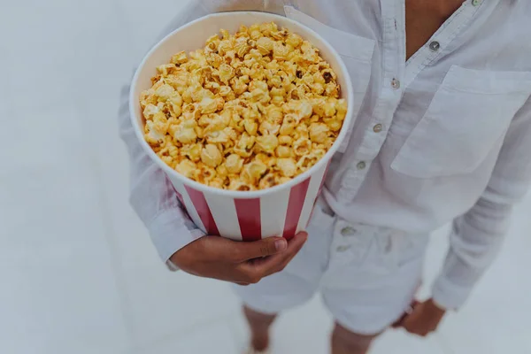 Close-up foto van een jong lief meisje, die een tube popcorn in haar handen houdt. — Stockfoto