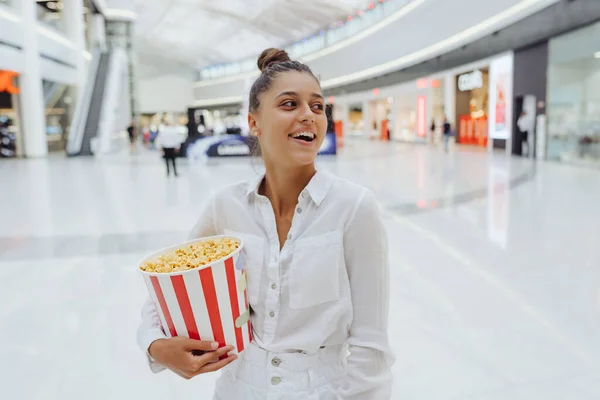 Junge süße Frau hält Popcorn im Hintergrund des Einkaufszentrums — Stockfoto