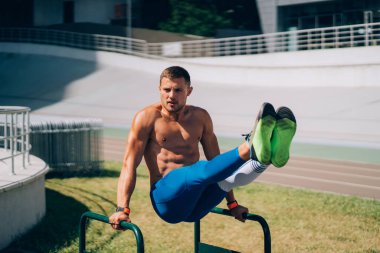 Açık hava spor salonunda düzgün olmayan barlarda egzersiz yapan güçlü bir adam..