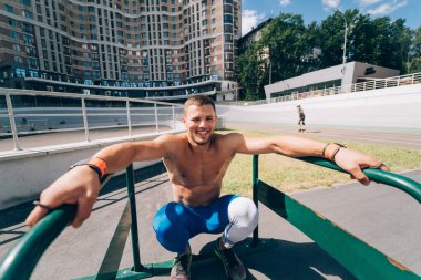 Açık hava spor salonunda düzgün olmayan barlarda egzersiz yapan güçlü bir adam..