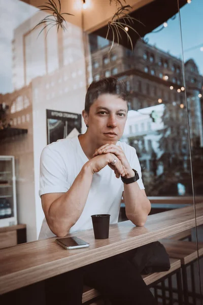Νέος, όμορφος άντρας πίνει τον πρωινό του καφέ σε ένα καφέ.. — Φωτογραφία Αρχείου
