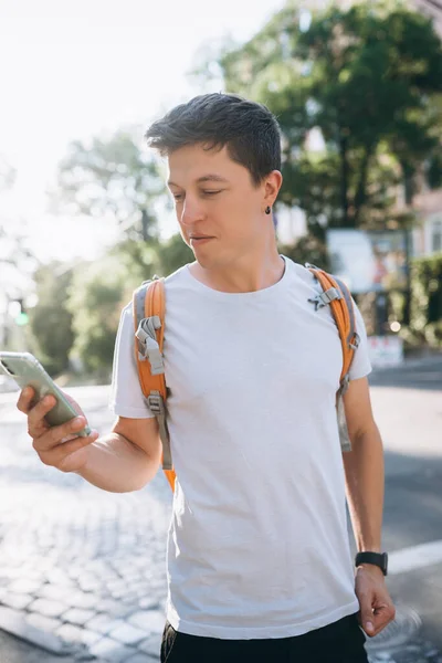 Портрет молодого чоловіка, який торкається мобільного екрану на вулиці — стокове фото