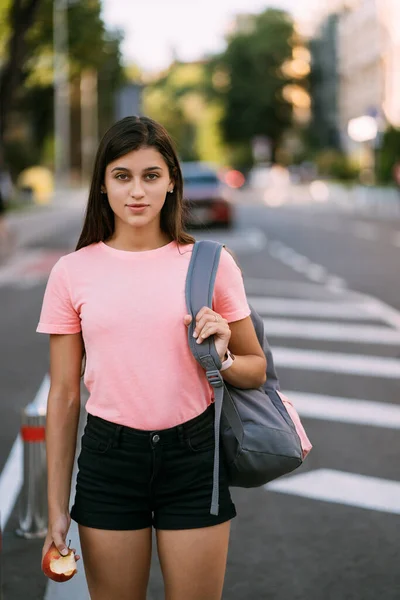 Молодая женщина держит яблоко на фоне улицы — стоковое фото