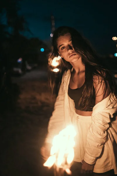 Молодая женщина с факелом на пляже ночью — стоковое фото