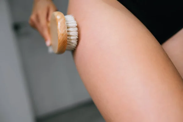 Menina acariciando a perna com um pincel no banheiro — Fotografia de Stock