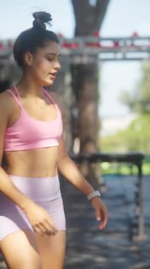 Kendini adamış bir sporcu, açık havada şık pembe spor giysileri giyerken çeşitli fitness alışkanlıkları geliştirir.