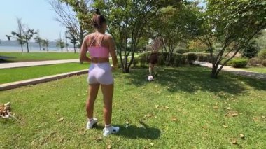 Güneşli ve keyifli bir günde, iki arkadaş canlı, yemyeşil bir park ortamında birlikte futbol oynamaktan mutlu olurlar.