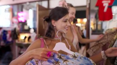 İki arkadaş modaya uygun bir mağazada renkli giysiler keşfedip, eğlenceli bir alışveriş deneyimi yaşıyorlar..