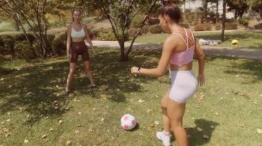İki yakın arkadaş güneşli bir park ortamında neşeli bir futbol antrenmanının keyfini çıkarıyorlar.