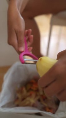 Bir insan patatesi ustalıkla kabın içine soyar. Mutfak becerilerini ve yemek hazırlama tekniklerini gösterir.