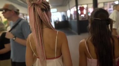 İki yakın arkadaş, şık sunumlar ve zevklerle dolu canlı bir pazar yerinde neşeyle geziniyorlar.