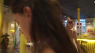 İki arkadaş şık aksesuarlar ve şık eşyalarla dolu canlı bir butikte mutlu bir şekilde alışveriş yapıyorlar.