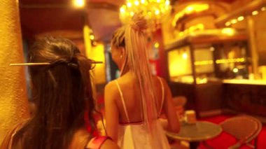 Ilık ışıklarla dolu canlı bir ortamda iki yakın arkadaş mutlu bir şekilde vakit geçiriyorlar.