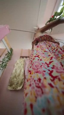 Şık bir kız renkli bir butiği keşfeder, canlı çiçekli giysiler ve şık bir çevreyi gösterir..