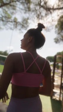 Parkta güneşli bir günün tadını çıkaran canlı spor kıyafetleri içindeki fit bir kadın atletik yaşam tarzını sergiliyor..