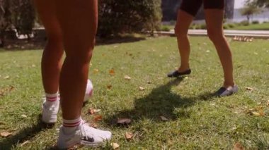 Güneşli bir günün tadını çıkaran iki yakın arkadaş parkta neşeli bir futbol topunu tekmeliyor.