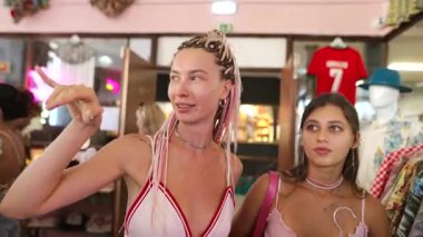 İki şık kadın canlı bir pazarda alışveriş yapmaktan, modaya uygun kıyafetler giymekten ve hareketli etkileşimlerden hoşlanırlar..