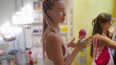 Bir grup genç kız renkli moda tarzlarıyla dolu canlı bir butikle neşe içinde moda kıyafetlerini keşfediyorlar.