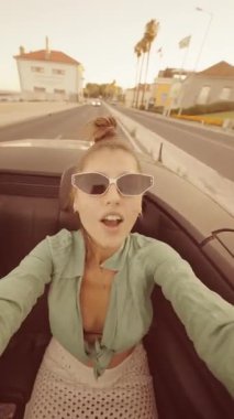 Güneşli bir günde özgürlüğün ve sevincin özünü yakalayan şık, üstü açık bir arabada heyecan verici bir an.