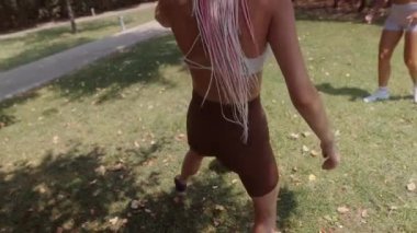 Açık havada renkli spor kıyafetleriyle futbol oynayan bir grup aktif kız güzel, güneşli bir günün tadını çıkarıyorlar.