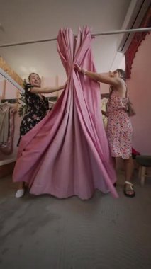 İki yakın arkadaş canlı pembe bir soyunma odasında keyifli ve eğlenceli bir moda tryon deneyimi yaşıyorlar.