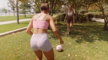 İki yakın arkadaş, güzel doğa ve yeşilliklerle çevrili güneşli bir parkta futbol oynamaktan büyük keyif alırlar.