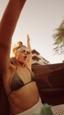 Güneşin çarpıcı batışı sırasında üstü açık bir arabada çekilen neşeli ve keyifli bir an.