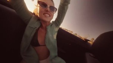 Güneşli bir günde saf neşe ve özgürlük sunan üstü açık bir arabada geçen heyecanlı bir an.