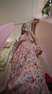 Rengarenk ve sanatsal bir odada büyüleyici bir model zarif bir şekilde çiçek desenli bir elbise giyiyor.