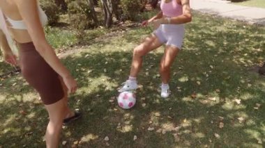 Güneşli bir günde, dışarıda neşeyle futbol oynayan iki genç kadın heyecan ve kahkahayla dolu.