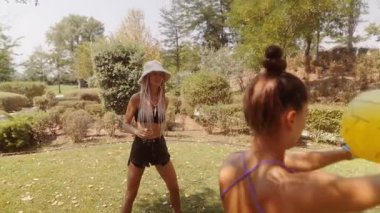 Güneşli bir günde arkadaşlarla harika vakit geçirirken yemyeşil bir parkta neşeli bir sarı topla oynarken.