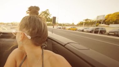 Üstü açık şık bir arabayla keyifli bir yaz gezisi. Parlak güneş ışığı altında neşeli anları yakalıyor.