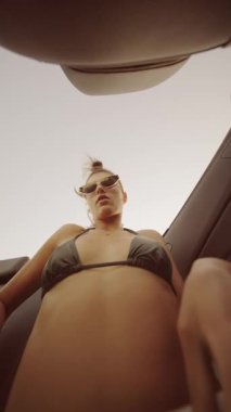 Şık bir kadın, güneş gözlüklü bir bikiniyle yaz tatilinden zevk alır. Yaşam tarzı ve plaj temaları için mükemmel..