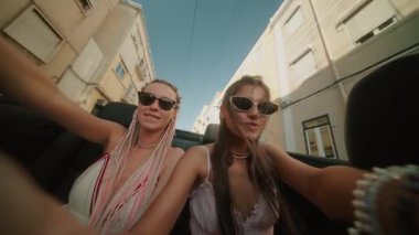 İki iyi arkadaş, canlı bir şehir caddesinde üstü açık bir arabada güneşli bir yolculuğun keyfini çıkarırken mutluluğu hisseder.
