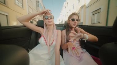 İki arkadaş üstü açık bir arabada güneşli bir günün tadını çıkarıyorlar. Arkadaşlığın ve eğlencenin özünü yakalıyorlar.