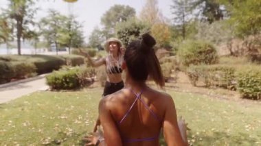 Bir grup arkadaş güneşli bir günde parkta voleybol oynarken keyifle eğleniyorlar.