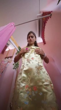 Şatafatlı altın bir elbiseyle süslenmiş göz kamaştırıcı bir manken, zarif elbisesini canlı pembe bir şekilde keşfediyor.