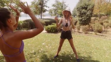 Güneşli güzel bir günde, iki arkadaş güzel yeşil bir parkta bir plaj topuyla oynayarak eğleniyorlar.