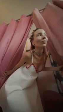 Harika stili olan genç bir kadın şık elbiseler sergiliyor. Parlak ve canlı bir soyunma odasında.