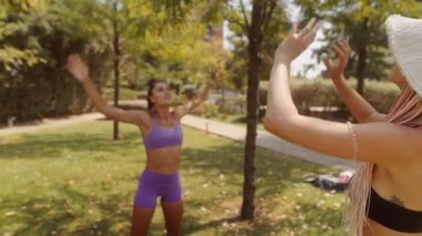 İki neşeli kadın güneşli bir parkta keyifli ve enerjik bir spor seansına katılıyor.