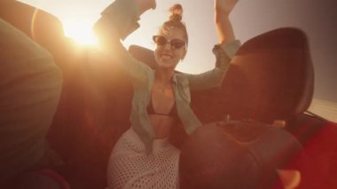 Canlı ve eğlenceli bir yolculuk sahnesi kaygısız anları yakalıyor sıcak güneşin altında üstü açık şık bir arabada paylaşılıyor.