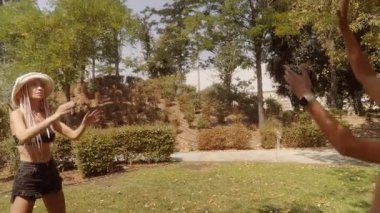 Güneşli bir parkta neşeyle top oynayan iki arkadaş, kahkaha ve eğlenceyle dolu mutlu bir yaz gününün tadını çıkarıyorlar.