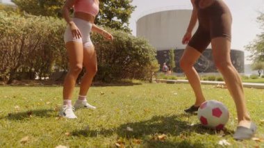 Güneşli bir günde, güzel bir parkta, iki kadın eğlenceli bir futbol seansının tadını çıkarıyorlar.