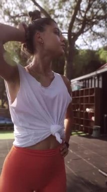 Formda ve sağlıklı bir kadın açık havada kendine güvenen bir poz verir, sakin ve doğal bir ortamda şık bir spor kıyafeti giyer.