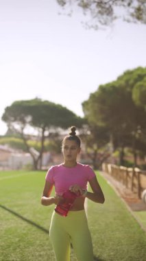 Canlı egzersiz kıyafetleri giymiş bir fitness meraklısı güneşli bir günde dışarıda keyifle egzersiz yapıyor.