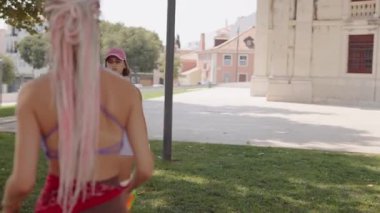 İki enerjik kadın güneşli bir parkta, atletizm ve spora olan sevgilerini sergileyerek eğlenceli bir raket oyunu oynuyorlar.