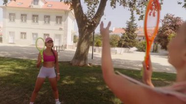 Bu güzel güneşli günde, iki arkadaş açık havada neşeli bir raket oyunu oynuyorlar.