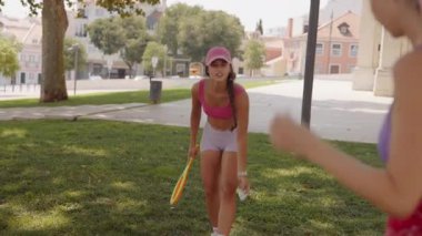 İki arkadaş güneşli bir park ortamında canlı bir tenis seansının keyfini çıkarıyorlar..