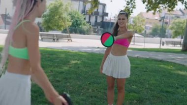 İki neşeli arkadaş sıcak güneş ışınlarının altında açık havada renkli kıyafetleriyle oynuyorlar.