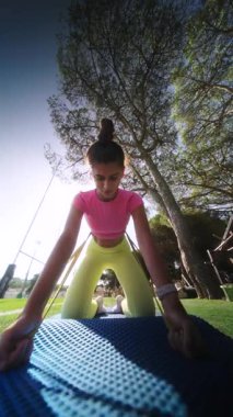 Güneşli bir ortamda mavi bir paspasın üzerinde yoga yapan bir insan, zindelik ve sağlığını gösteriyor..